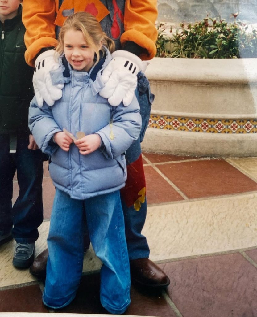 Lily as a child having a photo with a Disney character.