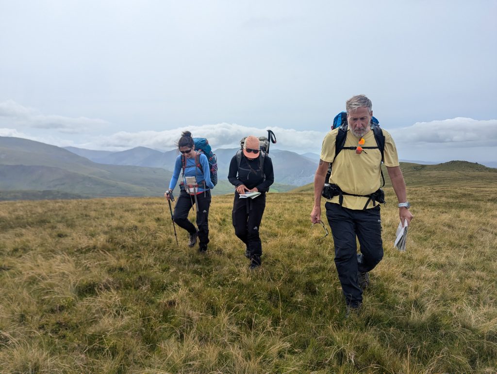 Max walking across a soggy heath, maps in hand, with other Mountain leaders during assessment